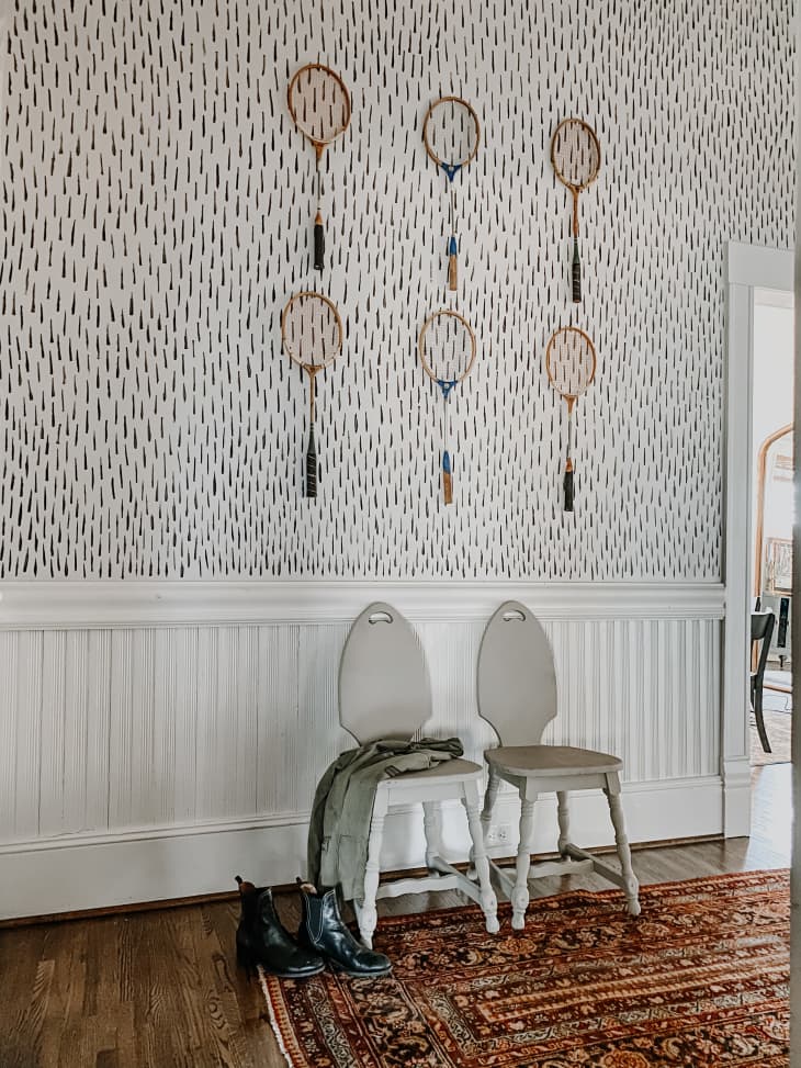 Hand-painted black and white walls in hallway with vintage racquets on display