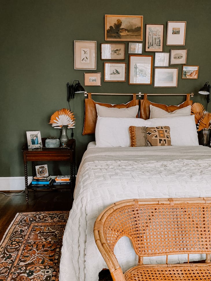 Bedroom with green walls and frames above leather headboard