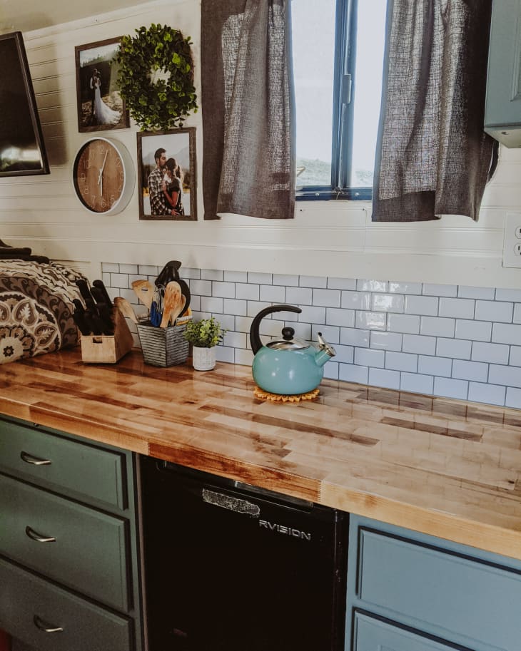 Kitchen with butcherblock countertops, blue-gray drawers, and subway tile backsplash