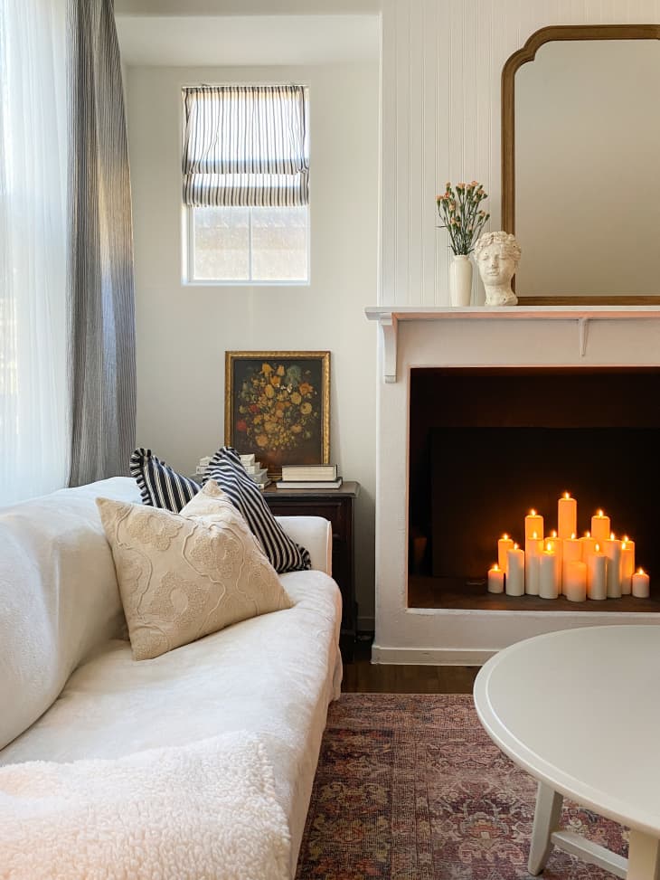 Fireplace with candles inside in mostly white living room