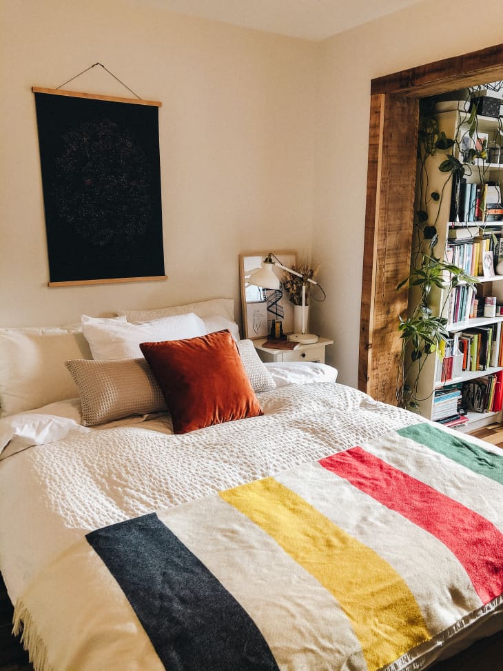Bedroom with Hudson's Bay blanket, cellestial wall art, and rust-colored pillow