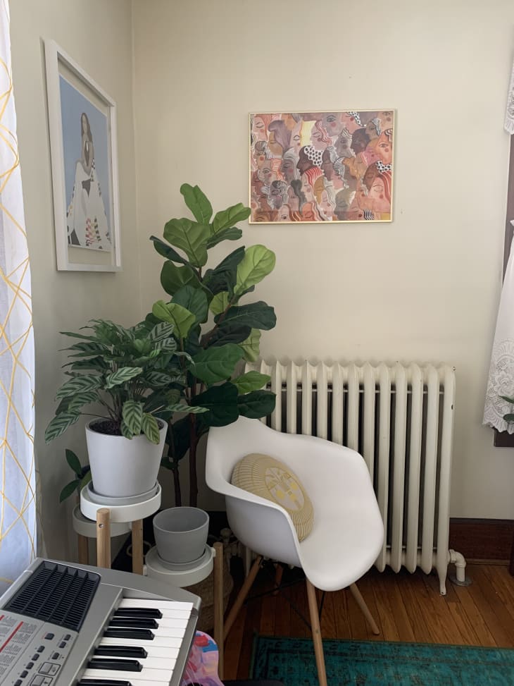 Modern white chair, plants, and radiator in corner next to keyboard