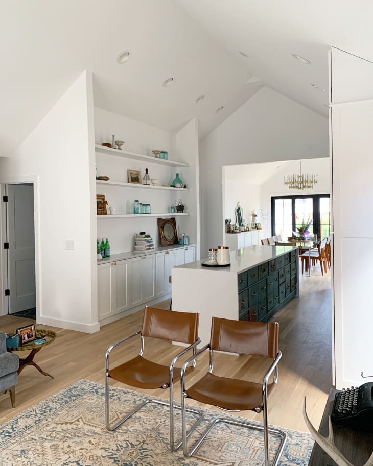 Two leather chairs in living room with bright white and open kitchen in background