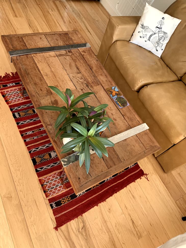 木制咖啡桌，红色地毯上有植物