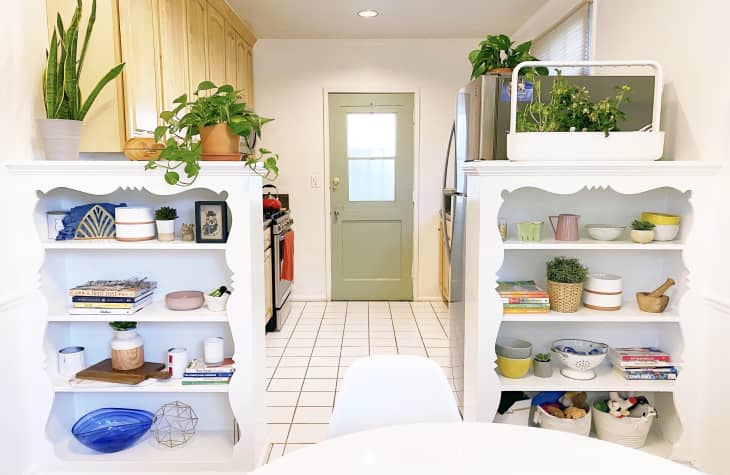 Plants and dishes on shelving that divides kitchen and dining areas