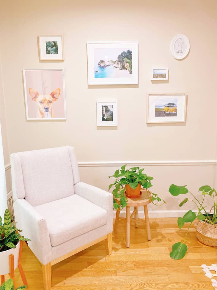 Plants and white mid-century-style chair in corner beneath gallery wall
