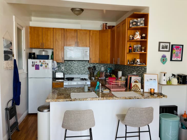 Kitchen with brown wooden cabinets, white appliances, Funko Pop toys on shelves, and teal tile backsplash