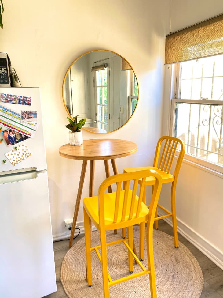Yellow barstools next to tall breakfast table and circular mirror in kitchen