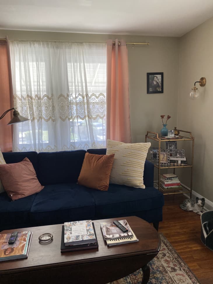 Navy sofa between window with pink curtains and brown coffee table