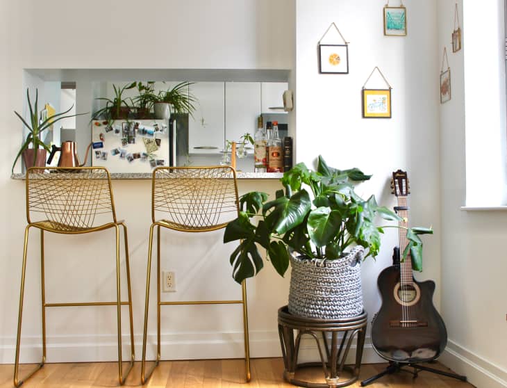 Gold barstools at kitchen counter. Plant and guitar in corner.