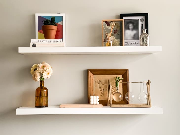 Two accessorized shelves with flowers, plants, small artwork, candle, and diffuser
