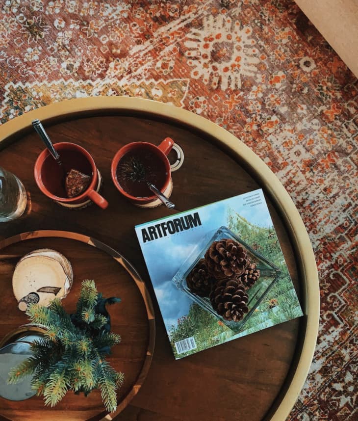 Close-up of coffee table with mugs, pinecones, greenery, and a book