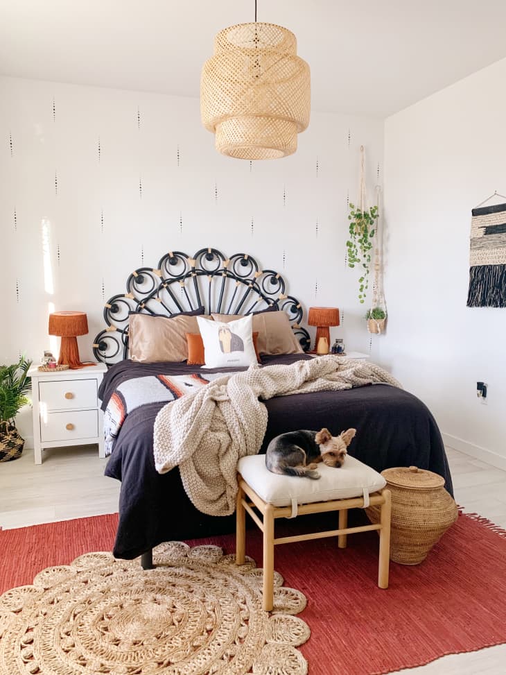 Bedroom with peacock headboard, orange fringe lamps on side tables, and boho pendant light
