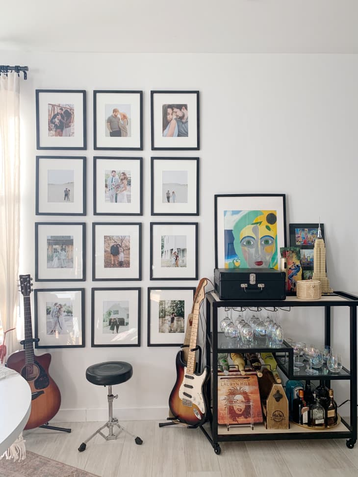 Photos in frames on wall next to guitars and stocked bar cart