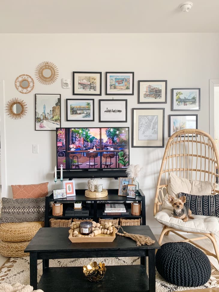 Living room with rattan chair, black coffee table and TV stand, and gallery wall