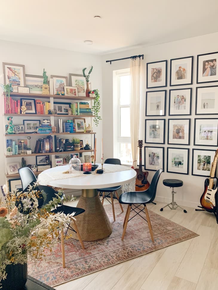 Dining area with round table, colorful books on shelves, and photos in frames