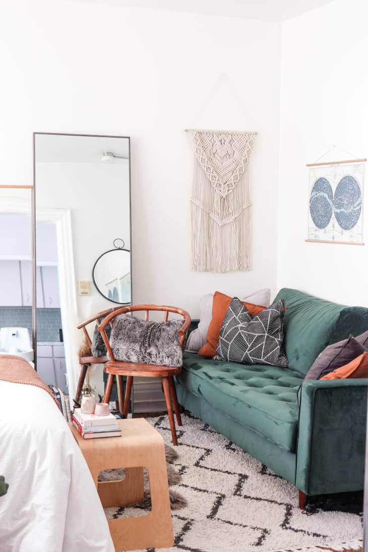 Green sofa, mirror, tapestry, and poster in corner