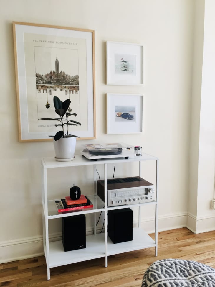 Record player, stereo, and speakers on white shelf underneath framed artwork