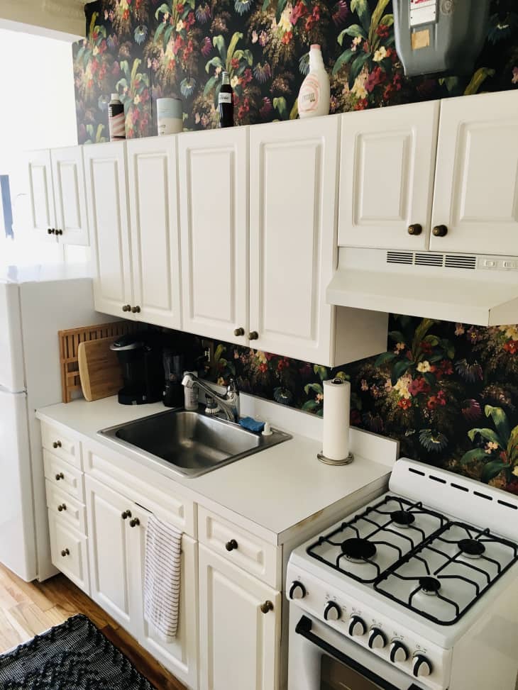 Kitchen with white cabinets and moody floral wallpaper