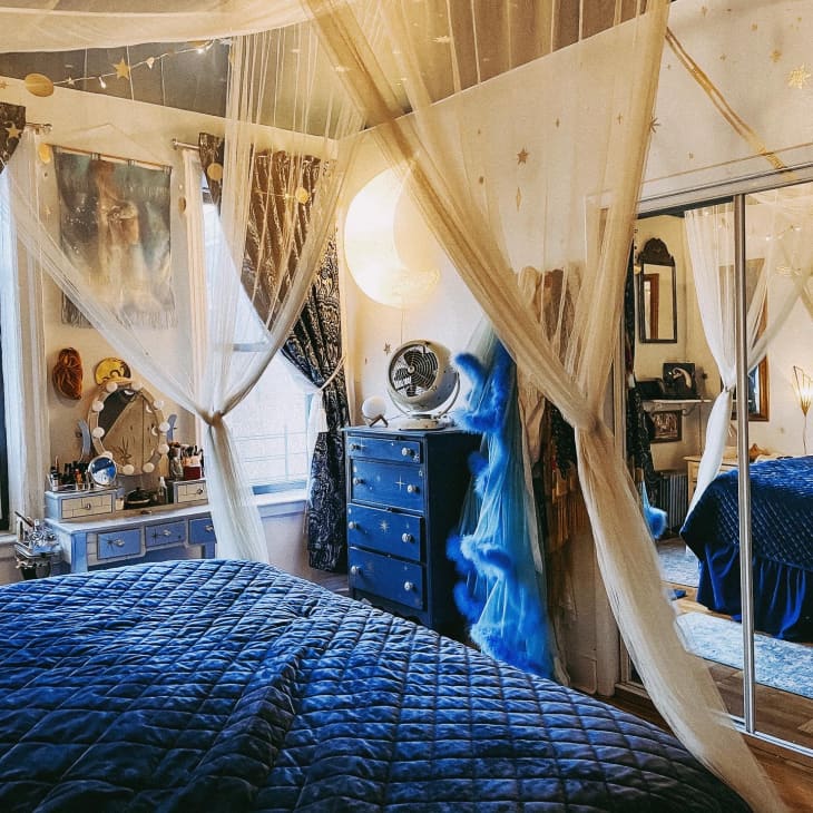 Bed with blue bedding and canopy and dresser in corner in bedroom