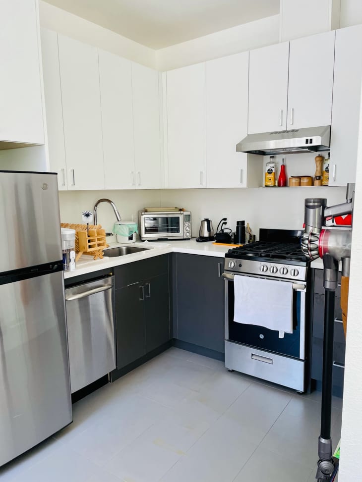 厨房有白色的上层橱柜，灰色的下层和不锈钢器具