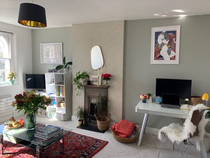 Sunlit living room with red rug, tv in corner, WFH setup in corner, and black drum-shaped pendant light