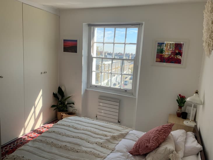 Bright bedroom with white walls and view of city street through window