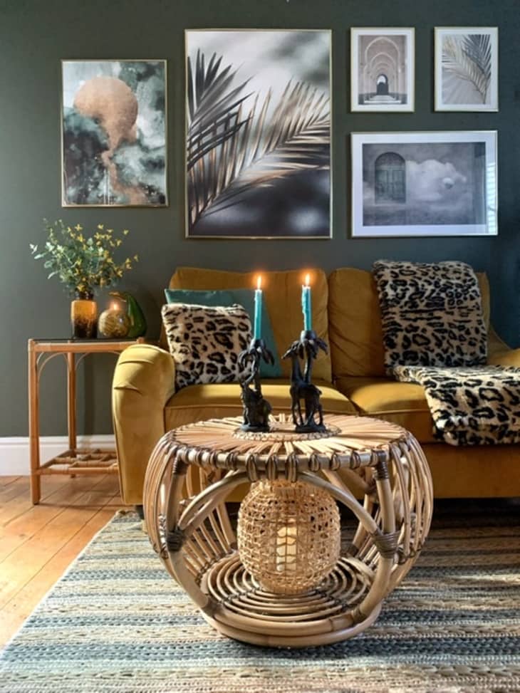 Rattan coffee table in front of gold sofa in living room with green walls