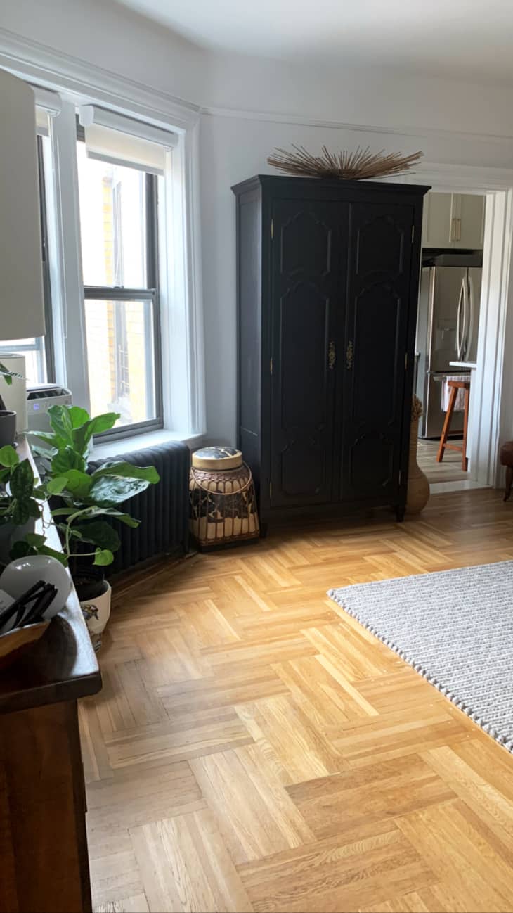 Room with parquet wood flooring and large dark wood storage cabinet