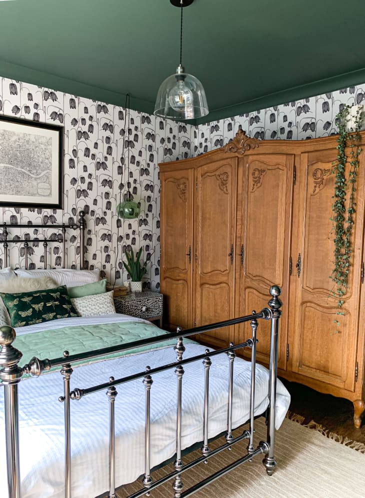 Bedroom with large antique armoire and black and white botanical wallpaper