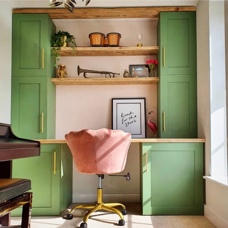 Home office with pink chair, pink walls, and green cabinets