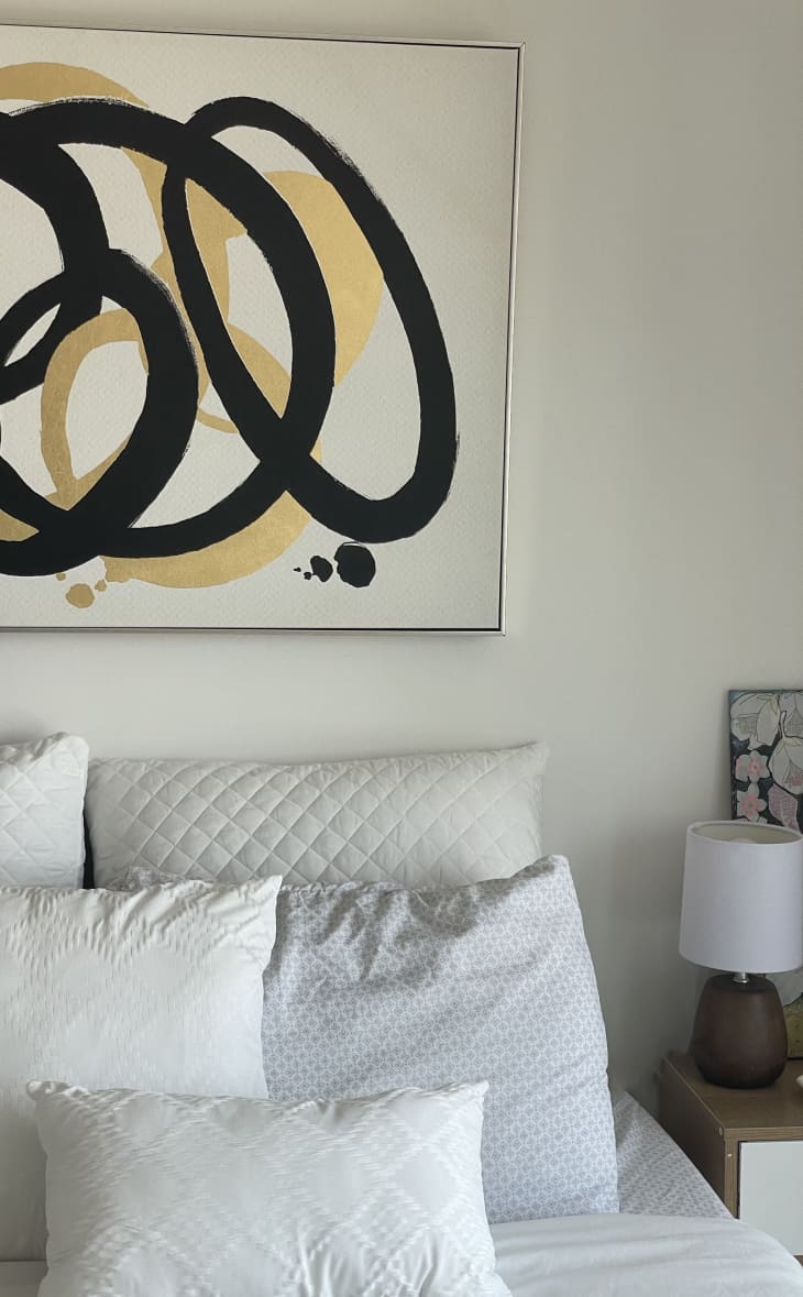 Bed with layered pillows and gold and black circle artwork above bed