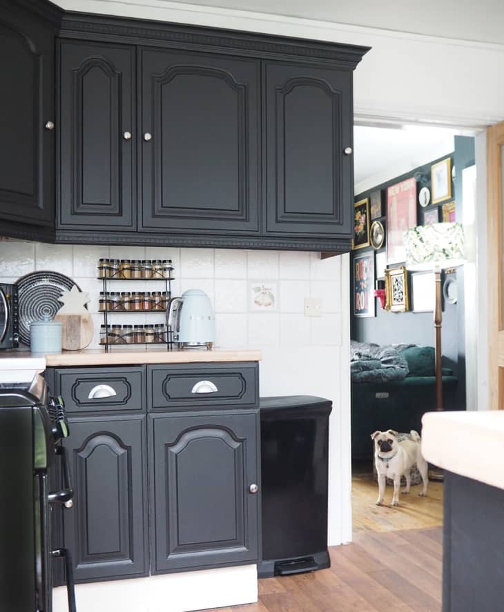 厨房炭灰色的橱柜，白色方形瓷砖后挡板，柜台上的香料架