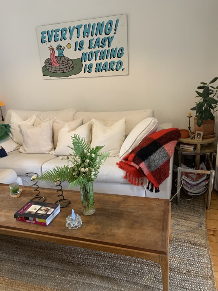 Living room with white sofa, wooden rectangular coffee table, and sign that says "Everything is easy! Nothing is hard."