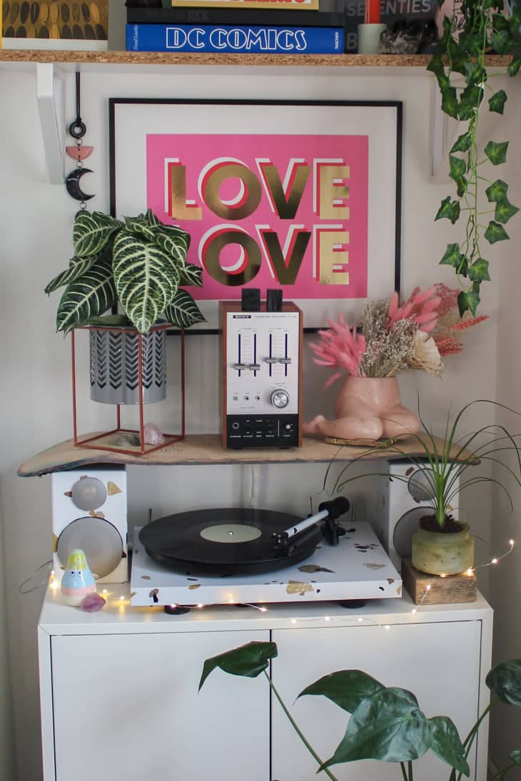 Turntable on cabinet surrounded by plants and "Love Love" artwork