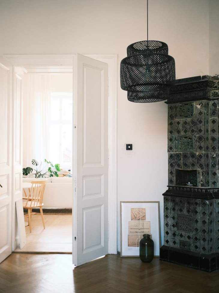Black rattan pendant light in front of old tile fireplace