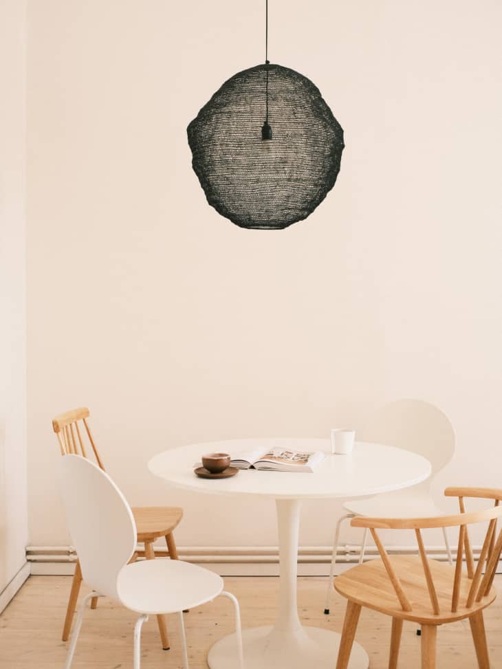 Round white tulip table with mismatched chairs and black modern pendant light above