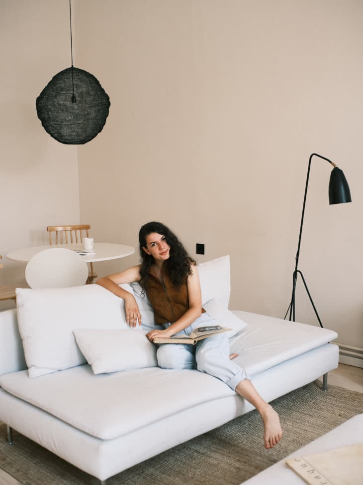 Woman sitting on white sofa in modern, minimalist home