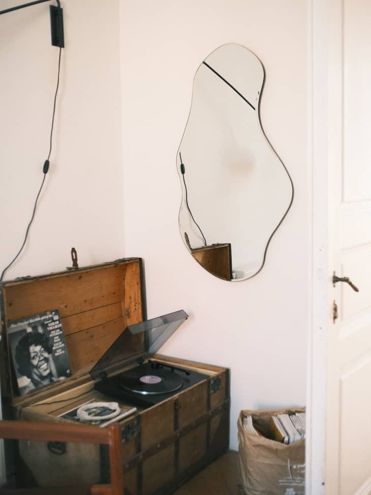 Wavy mirror hanging on wall in corner of room with record player