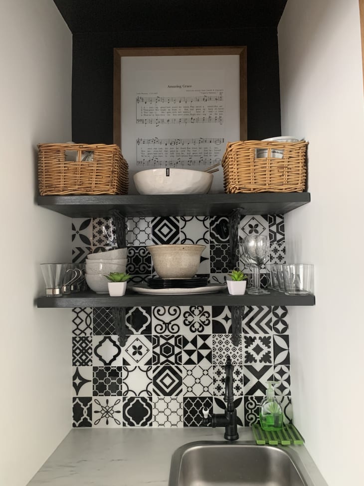 Shelves and black and white tile above small sink