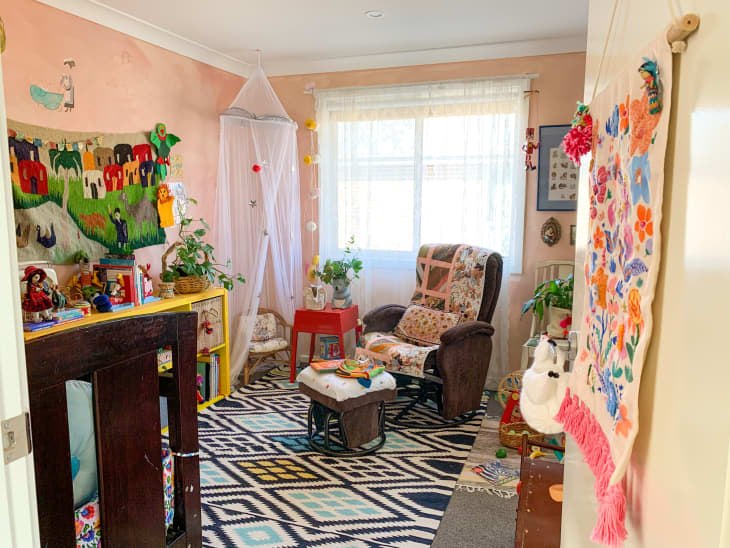 Colorful, vibrant nursery with pink walls and canopy in corner