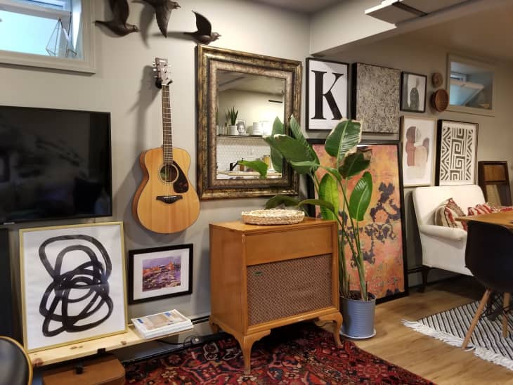 Living room wall featuring a vintage record player and large mirror on top of red vintage rug.