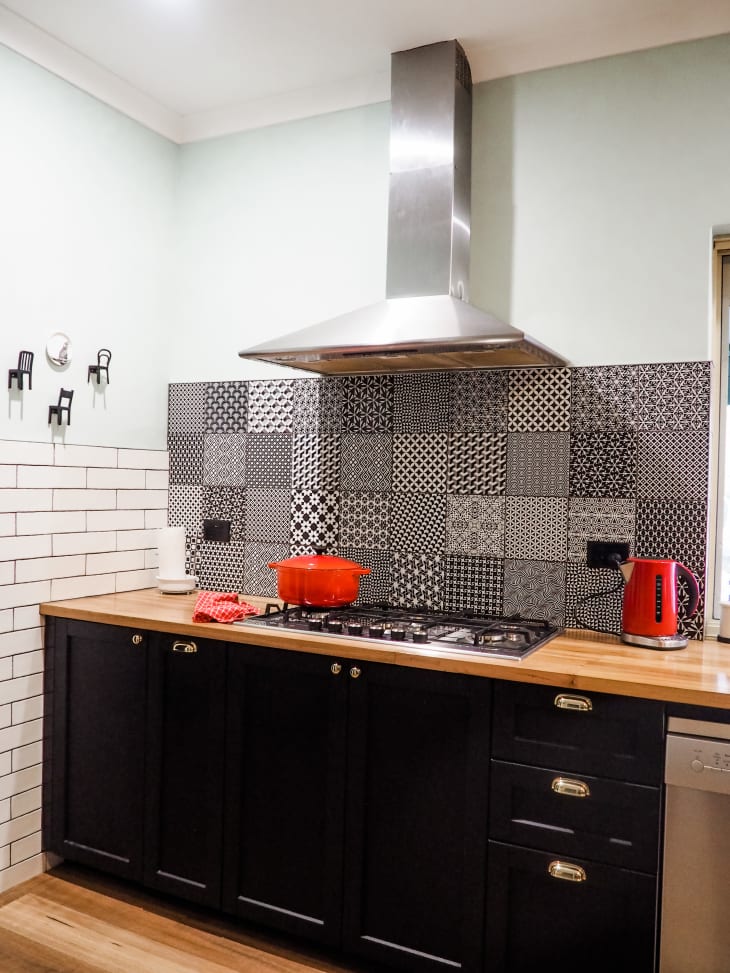 Range and hood in corner of kitchen with black and white patterned tile backsplash