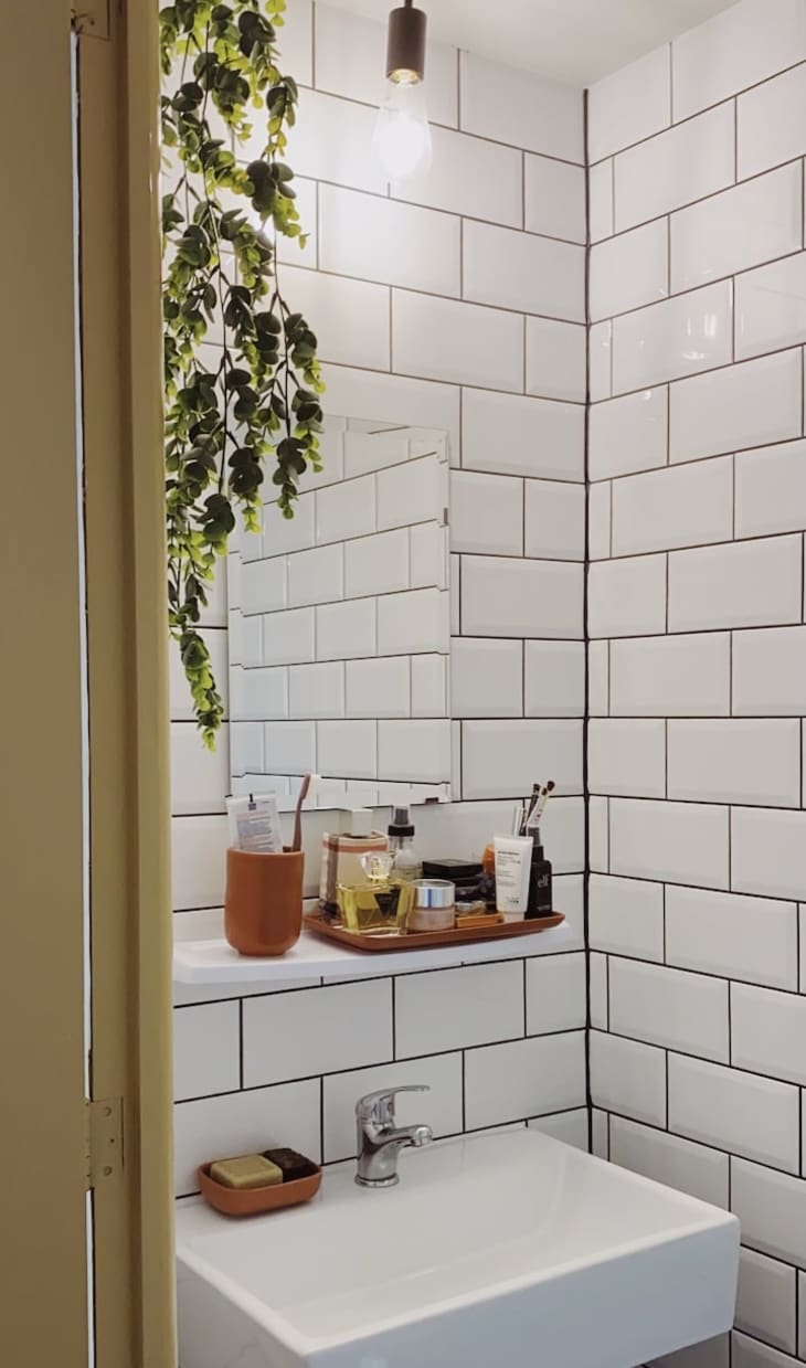 Sink in corner of bathroom with white subway tile