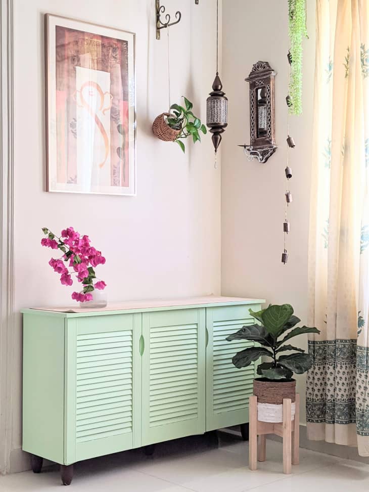 Mint green credenza in corner of room with light pink walls