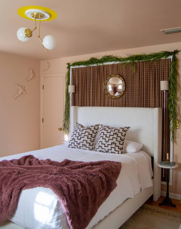 Bedroom with light pink walls and evergreen garland around headboard