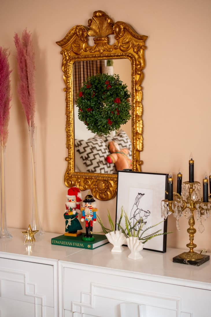 Wreath hanging on ornate gold-framed mirror above buffet
