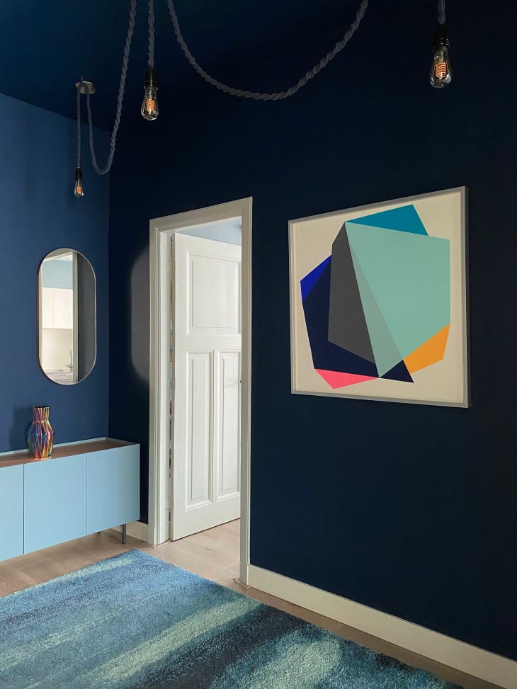 Room with navy walls and abstract artwork on the wall