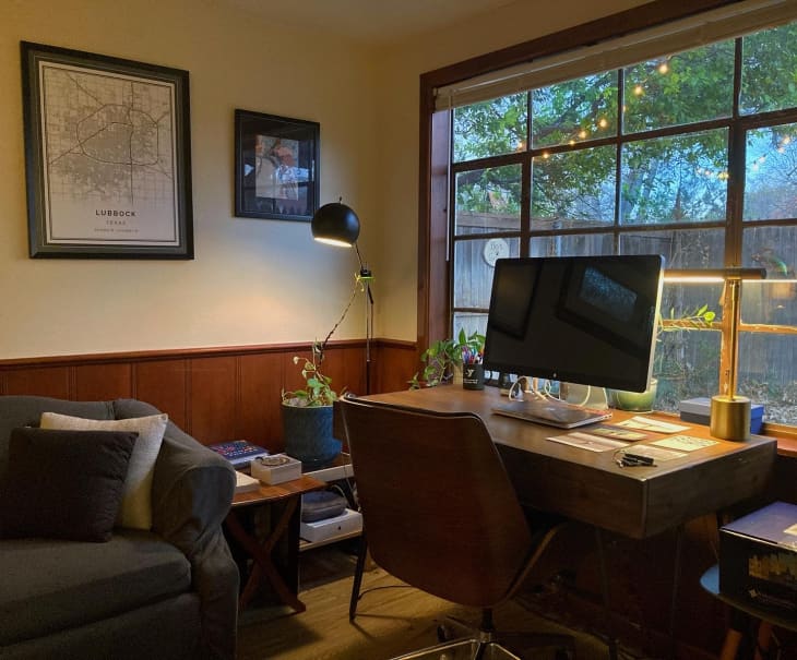Home office desk corner with large computer monitor and wood paneled half walls