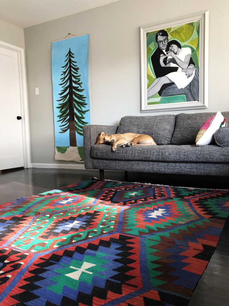 客厅里有大型艺术品，彩色的kilim地毯和灰色沙发